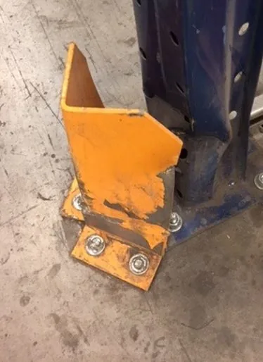 Yellow steel barrier twisted at its base, anchors visibly loosened