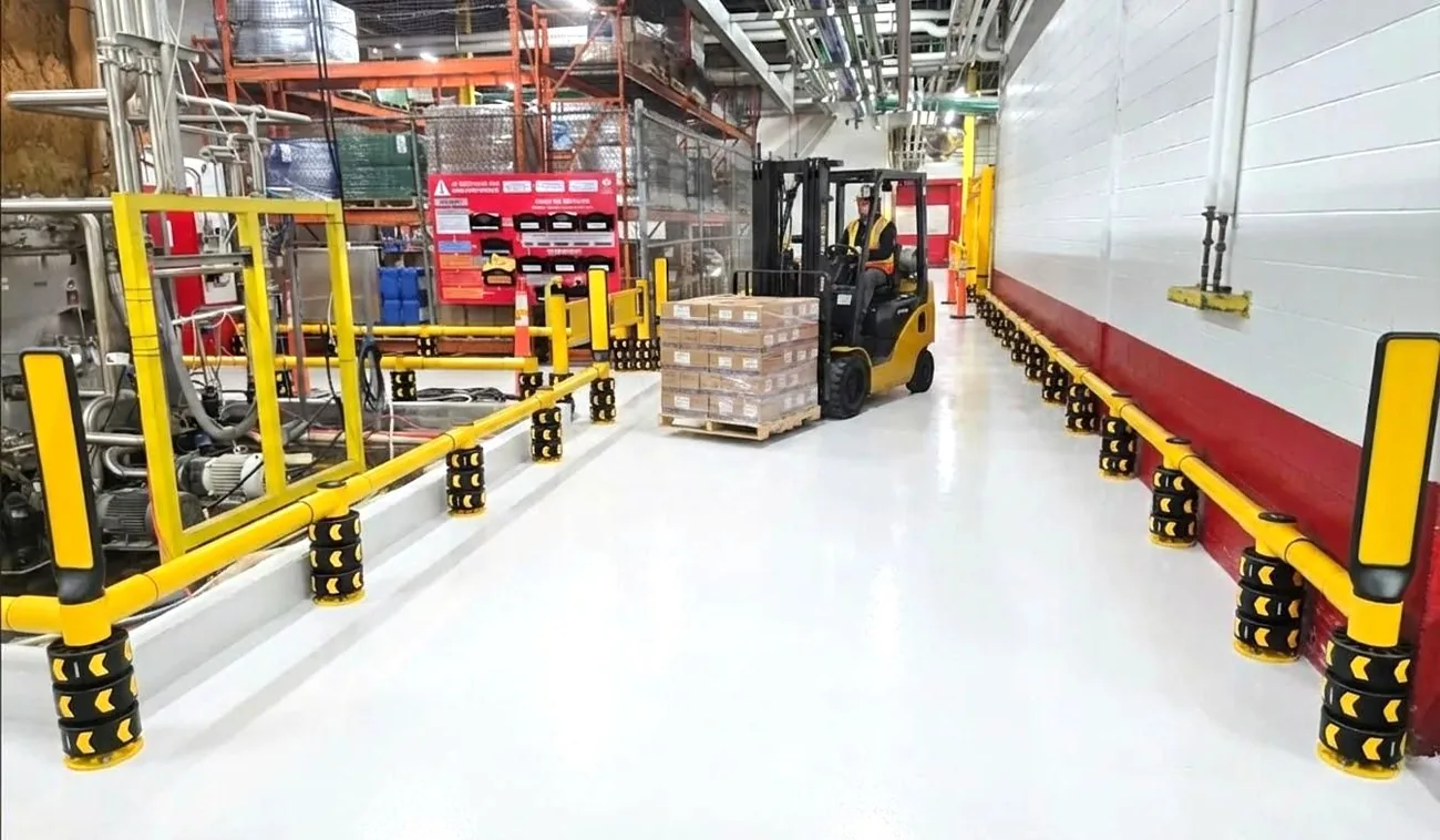 A bright, orderly distribution center with continuous ENNAT guardrails defining forklift and pedestrian zones